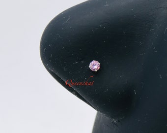 May include: A close-up of a pink gemstone nose ring stud on a black mannequin head. The ring is set in a silver setting.