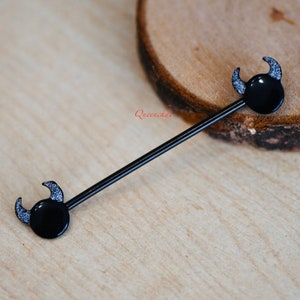 May include: Black barbell with black devil horns on each end. The horns have silver glitter on them.