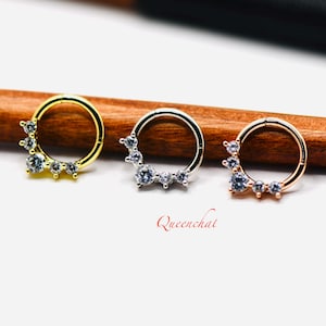 May include: Three hoop earrings with a row of clear cubic zirconia stones. The hoops are available in gold, silver, and rose gold.