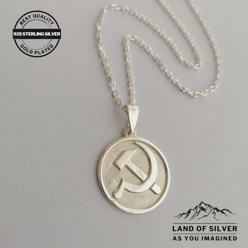 May include: Silver necklace with a round pendant featuring a hammer and sickle symbol. The pendant is gold plated and has a textured surface. The necklace is 925 sterling silver and is labeled "Best Quality Gold Plated 925 Sterling Silver".