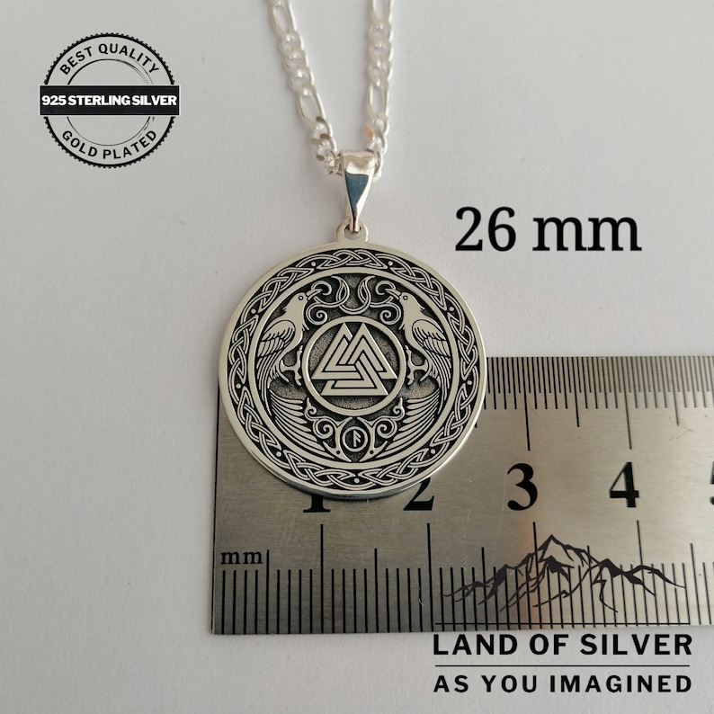 Pu&ograve; includere: Collana con ciondolo in argento di forma circolare decorato con un simbolo Vegvisir, due corvi e un bordo a nodo. Il ciondolo misura 26 mm di diametro. La collana &egrave; in argento sterling 925 e placcata oro.