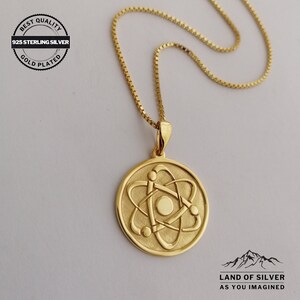 May include: Gold plated 925 sterling silver necklace with an atom pendant. The pendant is a round disc with a raised atom design. The chain is a box chain.