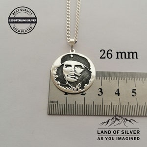May include: Silver pendant necklace featuring a profile portrait of a man with a star on his hat. The pendant is 26 mm in diameter and is on a silver chain. The pendant is on a white surface with a ruler for size reference. The text "BEST QUALITY 925 STERLING SILVER GOLD PLATED" is on a circular tag. The text "LAND OF SILVER AS YOU IMAGINED" is at the bottom of the image.