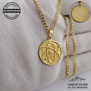 May include: Gold plated 925 sterling silver necklace with an atom pendant. The pendant is round and features a detailed atom design. The chain is a curb chain.