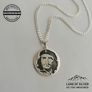 May include: Silver necklace with a round pendant featuring a black and white image of Che Guevara. The pendant has a star on the hat. The chain is silver and has a curb link style. The necklace is labeled "925 Sterling Silver Gold Plated" and "Land of Silver As You Imagined".