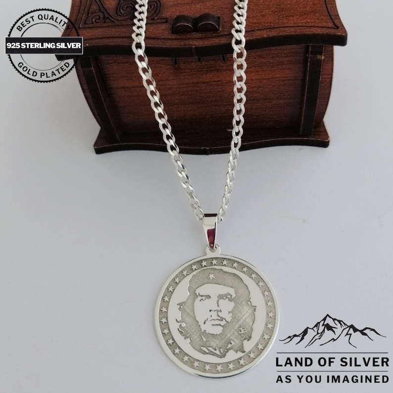 May include: A silver chain necklace with a round pendant featuring a profile portrait of a man with a beard. The pendant is surrounded by a circle of small stars. The text "LAND OF SILVER AS YOU IMAGINED" is printed below the pendant.