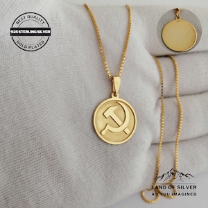 May include: Gold plated 925 sterling silver necklace with a round pendant featuring a hammer and sickle design. The pendant is on a delicate chain.