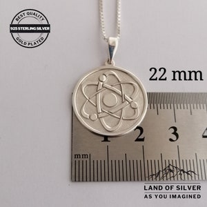May include: Silver necklace with a 22 mm round pendant featuring a detailed atom design. The pendant is made of 925 sterling silver and is gold plated. The necklace is 22 mm in diameter.