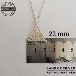 May include: Silver pendant necklace featuring an eye of Horus design inside a triangle with a small ankh symbol above. The pendant measures 22 mm in diameter. The pendant is on a silver chain and is labeled "925 Sterling Silver Gold Plated".