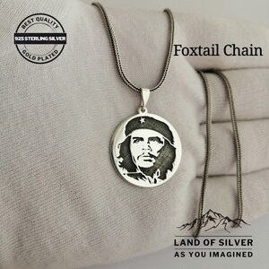 May include: A silver necklace with a round pendant featuring a profile portrait of a man with a star on his hat. The necklace is on a white surface and the text "Foxtail Chain" is visible in the image. The text "BEST QUALITY 925 STERLING SILVER GOLD PLATED" is also visible in the image. The text "LAND OF SILVER AS YOU IMAGINED" is also visible in the image.
