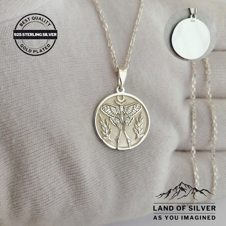 May include: A silver pendant necklace with a detailed moth design within a circular frame, hanging from a fine chain. The pendant features a crescent moon above the moth. The image includes text: "BEST QUALITY 925 STERLING SILVER GOLD PLATED".