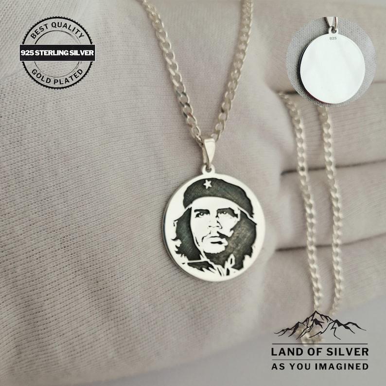 May include: A silver chain necklace with a round pendant featuring a black and white silhouette of Che Guevara. The pendant is engraved with a star and the text "925". The chain is a curb chain style. The necklace is on a white background.