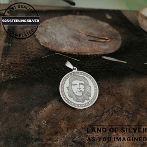 May include: A silver pendant featuring a portrait of Che Guevara, surrounded by a circle of stars. The pendant is made of 925 sterling silver and is gold plated. The text "BEST QUALITY 925 STERLING SILVER GOLD PLATED" is visible on the top of the image. The text "LAND OF SILVER AS YOU IMAGINED" is visible at the bottom of the image.