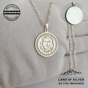 May include: Silver necklace with a round pendant featuring a profile of Che Guevara. The pendant is surrounded by a circle of stars. The necklace is 925 sterling silver and gold plated. The text "BEST QUALITY 925 STERLING SILVER GOLD PLATED" is on a tag attached to the necklace. The text "LAND OF SILVER AS YOU IMAGINED" is at the bottom of the image.