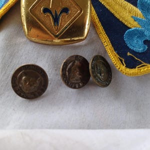 May include: Three gold-colored metal buttons with a blue and white design. The buttons have the text "BOY SCOUTS OF AMERICA" on them.