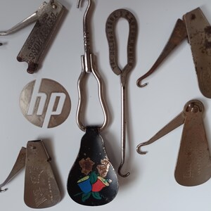 May include: A collection of seven vintage shoe horn tools. The tools are made of metal and have different designs. Some of the tools have a hook on the end, while others have a flat, rounded end. The tools are all in good condition and have a patina from age.