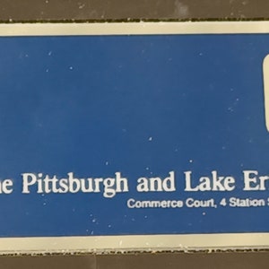 May include: A blue and white sign with the text "The Pittsburgh and Lake Erie Railroad Company" and the address "Commerce Court, 4 Station Square, Pittsburgh, Pa, 15219 4".