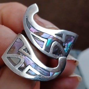 May include: A pair of silver earrings with a geometric design and iridescent abalone shell inlay.