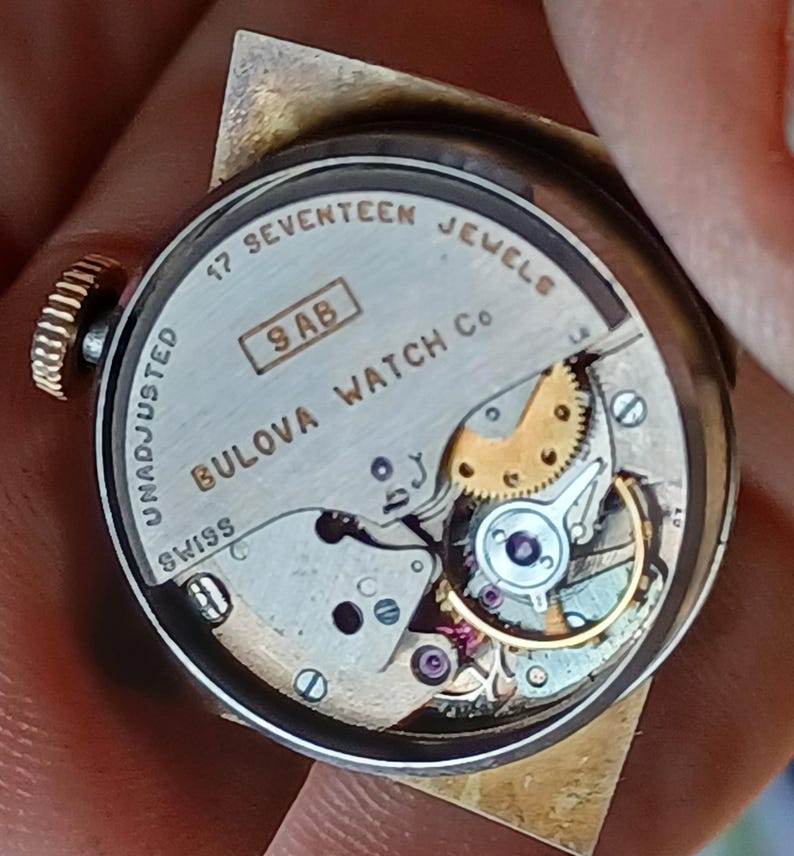 K&ouml;nnte beinhalten: Die R&uuml;ckseite einer silbernen Bulova-Uhr mit einem 17-Steine-Werk. Die Uhr ist mit "Bulova Watch Co. Swiss" und "17 Seventeen Jewels" beschriftet und hat die Seriennummer "9 AB".