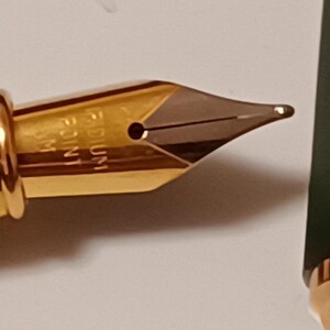 Puede incluir: Una plumilla de pluma estilogr&aacute;fica dorada con una punta mediana, etiquetada como "MEDIUM 1.1 MM".