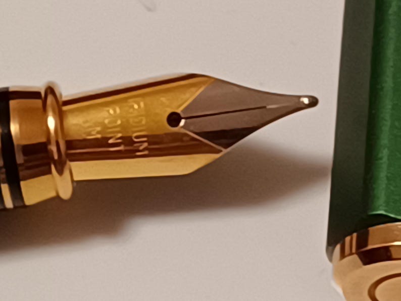 Puede incluir: Una plumilla de pluma estilogr&aacute;fica dorada con una punta mediana, etiquetada como "MEDIUM 1.1 MM".