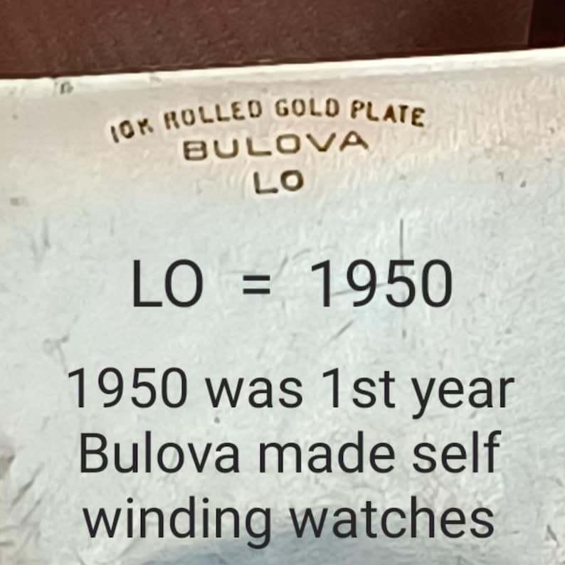 K&ouml;nnte beinhalten: Nahaufnahme einer Uhreninschrift mit der Aufschrift "10K Rolled Gold Plate Bulova LO" und "LO = 1950". Die Inschrift lautet weiter: "1950 was 1st year Bulova made self winding watches."