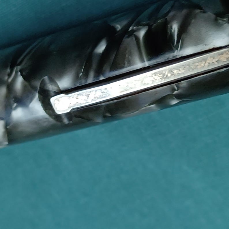 May include: Close-up of a pen with a silver clip and a black and gray marbled barrel. The pen is set against a teal background. The clip has a decorative design.