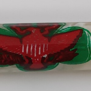 May include: A clear, rectangular pen with a white, pearlescent finish. The pen features a red eagle emblem with green and white accents. The eagle is centered on the pen's barrel.
