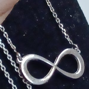 May include: A silver infinity symbol pendant necklace with a delicate chain.