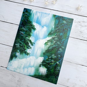 May include: A painting of a waterfall cascading down a rocky cliff, surrounded by lush green trees. The water is white and blue, and the trees are a deep green.