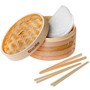 May include: A bamboo steamer with an open lid, showing a stack of white paper liners. Three pairs of wooden chopsticks are also present. The brand name "Blauke" is printed on the side of the steamer.