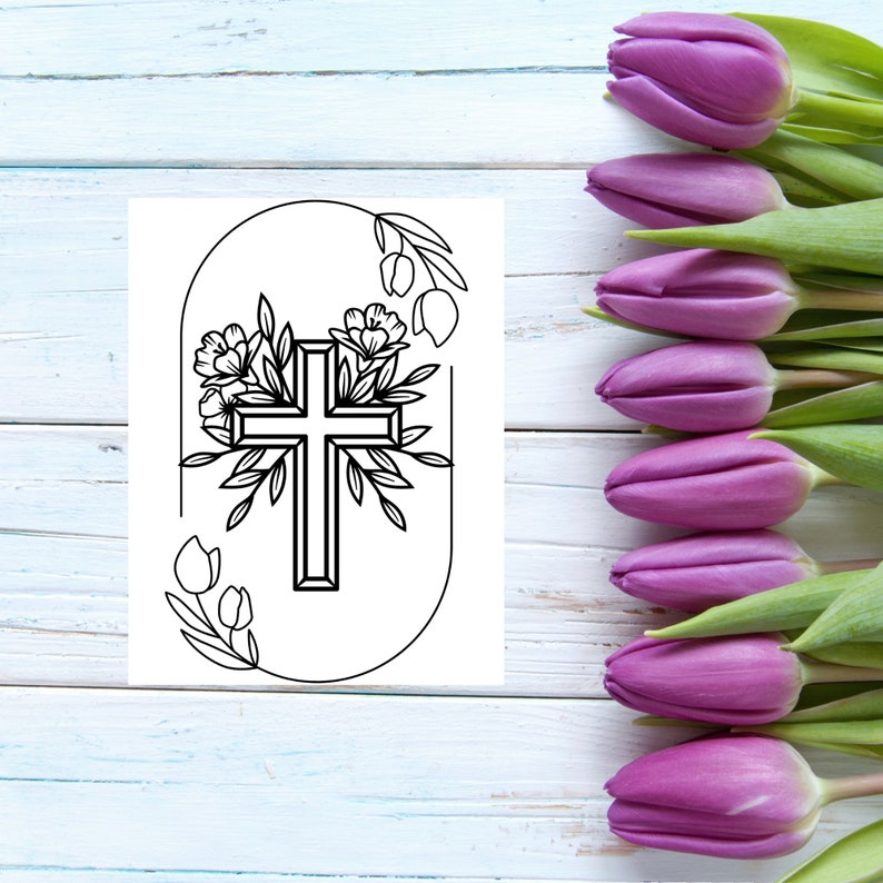May include: A black and white line drawing of a cross with flowers and leaves around it. The cross is inside a circle with a rounded top. The background is a white wooden surface with purple tulips on the right side.