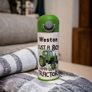 May include: A white insulated water bottle with a green lid and a green tractor graphic. The bottle has the text "Weston Just A Boy Who Loves Tractors" printed on it.