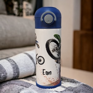 May include: A blue and white stainless steel water bottle with a blue lid and a graphic of a dirt bike and the name "Ean".
