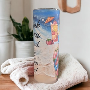 May include: A tall, clear tumbler with a colorful design featuring a beach scene, waves, flip flops, and cocktails. The text "I think my happy place is the beach" is printed on the tumbler.