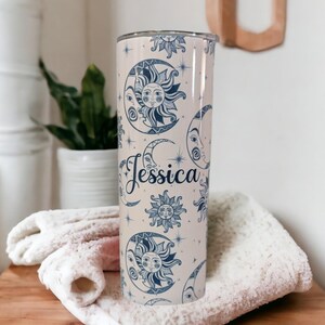 May include: A personalized stainless steel tumbler with a cream background and a blue and white sun and moon pattern. The name "Jessica" is printed in a cursive font on the tumbler.