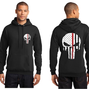 May include: Black hooded sweatshirt with a white distressed skull graphic featuring an American flag with a red stripe down the middle. The skull is on the front of the sweatshirt and the back of the sweatshirt.