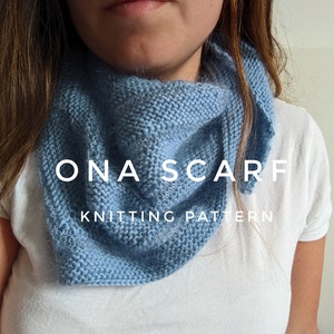 Puede incluir: Una bufanda de punto azul claro con el texto "ONA SCARF KNITTING PATTERN" en ella.