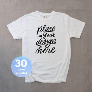 May include: A white short-sleeved t-shirt featuring black cursive text that reads place Your design here with an arrow pointing left. A light blue circular badge in the bottom left corner displays the white text 30 colors included.