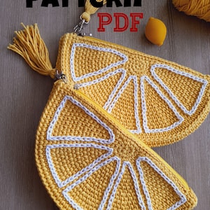 May include: A crochet lemon-shaped zippered pouch with a white tassel. The pouch is made of yellow yarn and has a white crocheted design. The text "PATTERN PDF" is visible in the image.