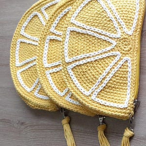 May include: Three crocheted lemon-shaped zippered pouches with yellow and white yarn. Each pouch has a yellow tassel.