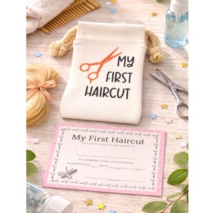 Può includere: Un sacchetto color crema con la scritta "MY FIRST HAIRCUT" e forbici arancioni. È presente anche un certificato rosa con lo stesso testo e l'illustrazione delle forbici, insieme a un paio di forbici, un pettine e un piccolo flacone spray.