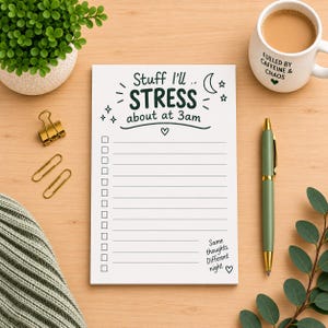May include: A white rectangular notepad with black text that reads Stuff I'll STRESS about at 3am, featuring a checklist with horizontal lines, a crescent moon, stars, and a heart. The bottom right corner includes the text Same thoughts. Different night.
