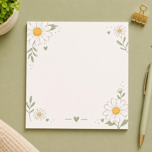 Peut inclure: Un bloc-notes carré avec un fond blanc orné de marguerites illustrées dans les coins supérieur gauche et inférieur droit. Le motif comprend de petits cœurs verts et des tiges délicates avec des feuilles, offrant un espace pour écrire.