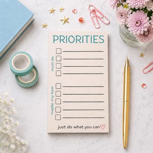 Peut inclure: Un bloc-notes rectangulaire au fond crème avec le texte PRIORITIES en bleu sarcelle en haut. Il comprend deux sections intitulées must do et maybe my best avec des cases à cocher et des lignes, se terminant par just do what you can et un cœur.