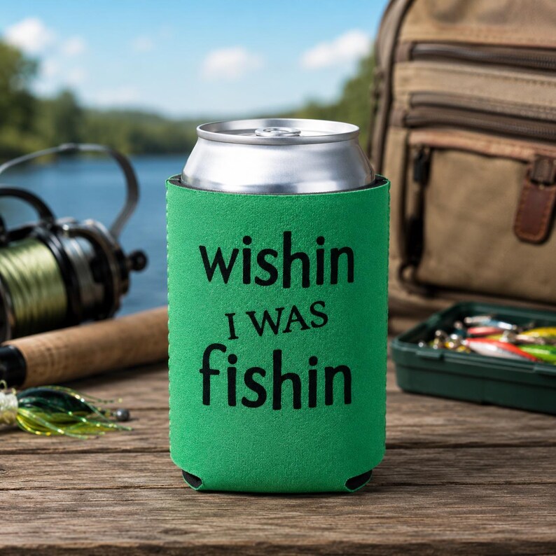 May include: A bright green foam can cooler sleeve featuring the black text "wishin I WAS fishin" printed on the front. The sleeve is cylindrical and designed to hold a standard metal beverage can, providing insulation for the container.