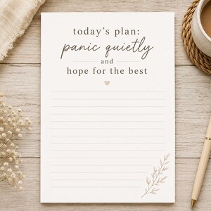 May include: A white rectangular notepad featuring horizontal lines and the printed text today's plan: panic quietly and hope for the best. The design includes a small heart icon and a delicate botanical illustration in the bottom right corner.