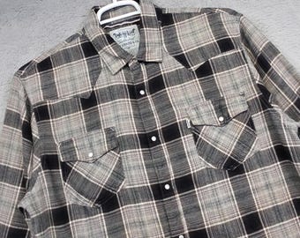 May include: A long-sleeved, button-down shirt in a plaid pattern of black, gray, and beige. The shirt has two chest pockets with button closures and a collar. The Levi Strauss & Co. label is visible at the neck.