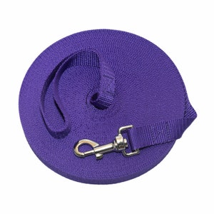 May include: A purple retractable dog lead with a silver clip. The lead is coiled up and ready to use.