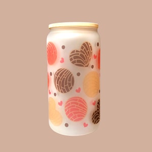 May include: A frosted glass jar with a wooden lid, featuring a repeating pattern of pink and brown heart-shaped pastries and small red hearts.